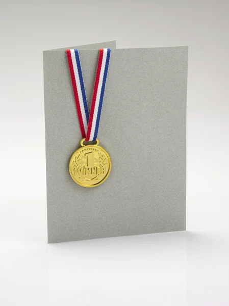 Золотая медаль на поздравительной открытке серого цвета — стоковое фото
