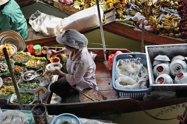 Таиланд, Бангкок, Тайская женщина готовит еду на деревянной лодке на Плавучем рынке — стоковое фото