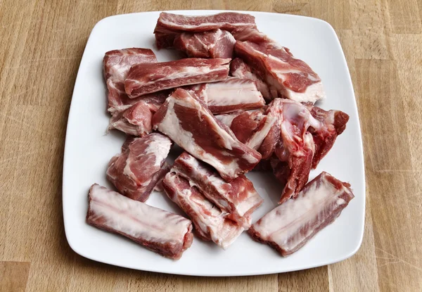 Côtes de porc non cuites sur un plat blanc — Photo
