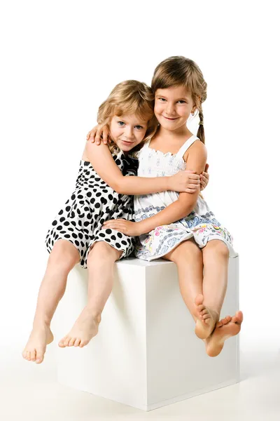 Twee kleine meisje vrienden samen zitten op geïsoleerde Wit Rechtenvrije Stockafbeeldingen