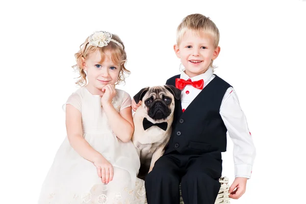 Małej dziewczynki i chłopca w klasycznym garniturze z mops pies na białym tle nad białym — Zdjęcie stockowe