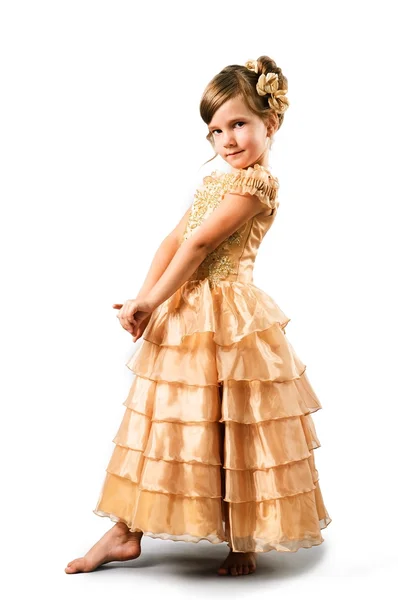 Malá dívka pózuje ve zlatých šatech izolovaných na bílém pozadí — Stock fotografie