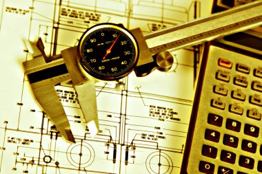 Grunge caliper and calculator over engineering drawing clipart