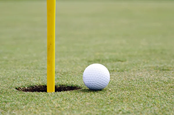 Мяч для гольфа на краю чашки — стоковое фото