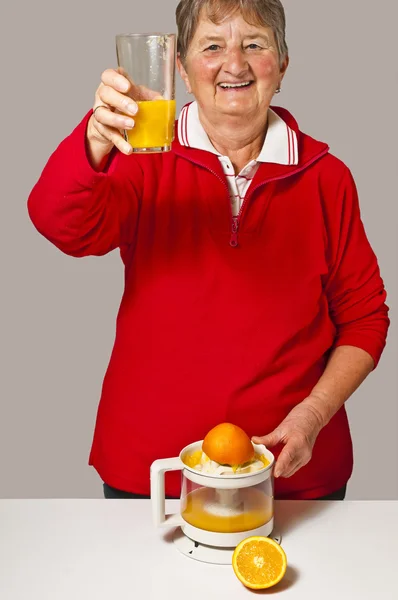Pensioner drinks orange juice — Stock Photo, Image