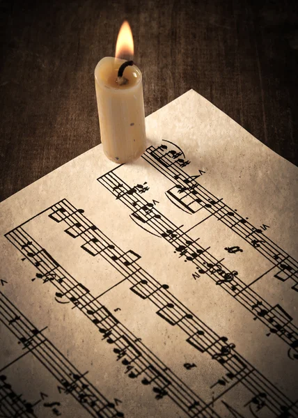 La candela illumina la carta musicale — Foto Stock