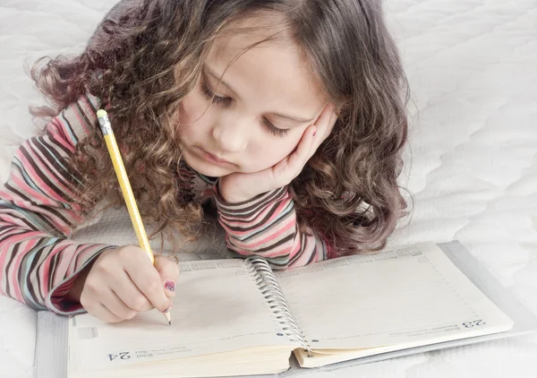 Kleines Mädchen mit Notizbuch und Stift — Stockfoto