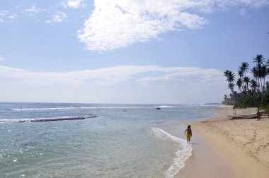 A man walking down the beach on a bright sunny day clipart