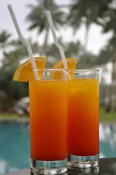 Twee glazen van tequila sunrise door een pool — Stockfoto
