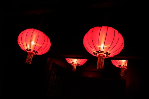 Kinesiske røde lanterner nær døren i natten af templet - Stock-foto