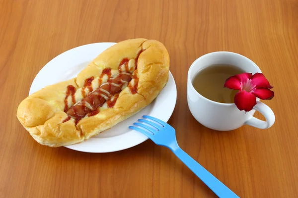 Λουκάνικο σαλάτα κρέμα και κέτσαπ ψωμί με τσάι στο τραπέζι. — Φωτογραφία Αρχείου