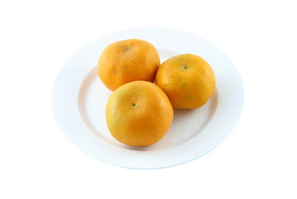 Три апельсина на тарілці на білому тлі . — стокове фото