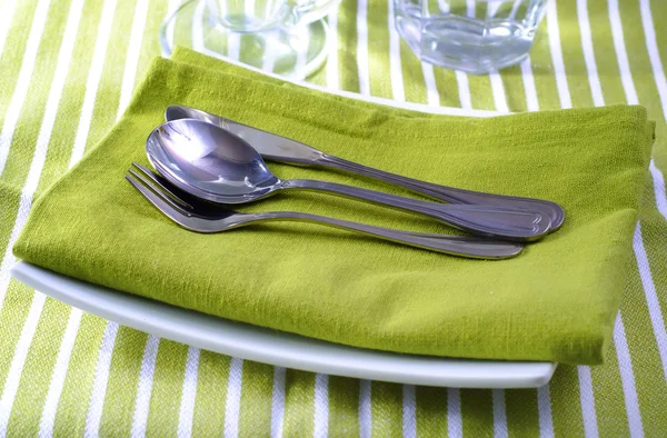 Place setting on green napkin and white plates — Stock Photo, Image