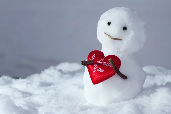 Bonhomme de neige drôle tient un cœur — Photo