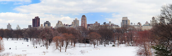 New York City Manhattan Central Park in winter city skyline panorama with snow and skyscrapers, cloudy blue sky.