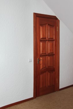 The wooden door in the room with sloping ceilings clipart