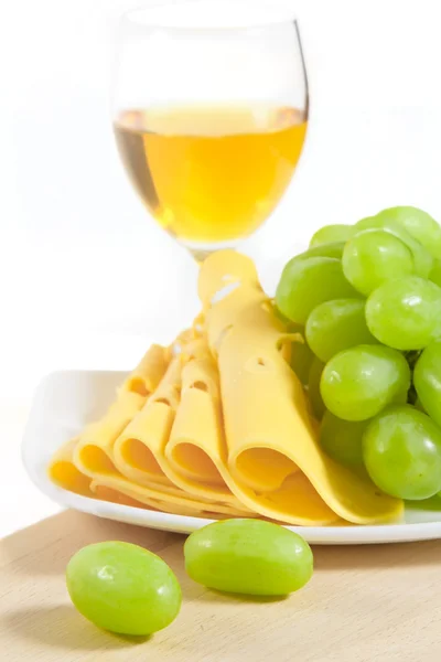 Un verre de vin blanc, de fromage tranché et de raisins verts sur bois — Photo
