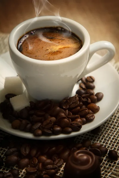 Pequeña taza de café fuerte sobre un fondo marrón con granos de café —  Fotos de Stock