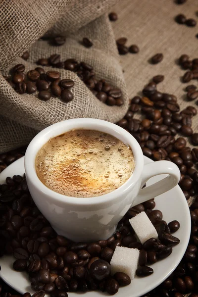 Piccola tazza di caffè forte su uno sfondo marrone con chicchi di caffè — Foto Stock