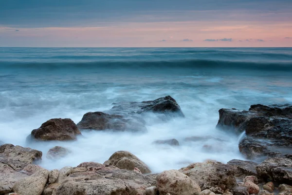 Красивий скелястий морський пляж на заході сонця — стокове фото