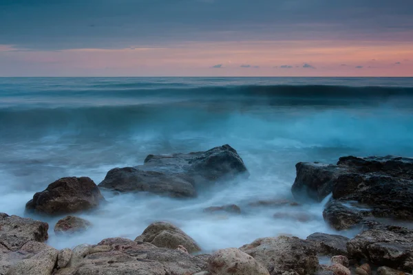 Gün batımında güzel kayalık deniz plaj — Stok fotoğraf