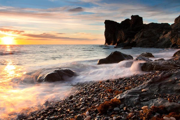 Красивий скелястий морський пляж на заході сонця — стокове фото