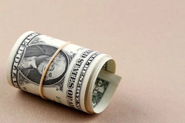 Rulla av dollar sedlar på enfärgad bakgrund — Stockfoto
