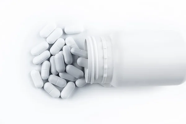 Píldoras que se derraman desde el contenedor sobre fondo liso —  Fotos de Stock