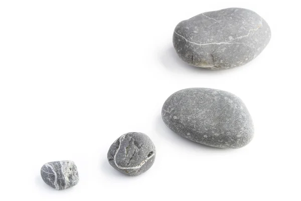 Quatro rochas de tamanho variado no fundo liso — Fotografia de Stock