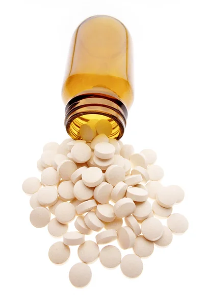 Pills spilling from bottle on plain background — Stock Photo, Image