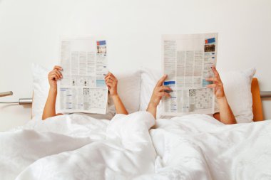 Reading a newspaper in bed clipart