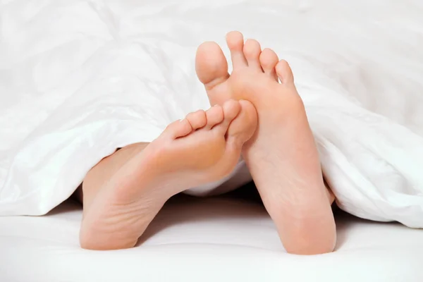 Nogi w łóżku — Zdjęcie stockowe