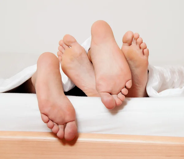 Fötter i ett par i sängen. — Stockfoto
