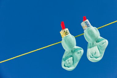 Baby socks on clothesline with swiss francs clipart