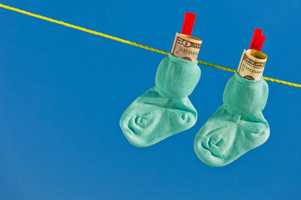 Baby socks on clothesline with dollar bills — Stock Photo, Image