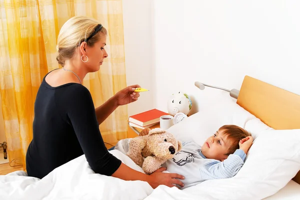Matka a nemocné dítě v posteli. — Stock fotografie