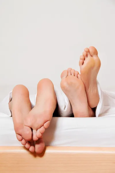 Nohy pár v posteli. — Stock fotografie