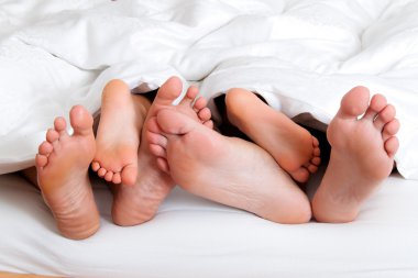 Soles of a family in bed under the ceiling. clipart