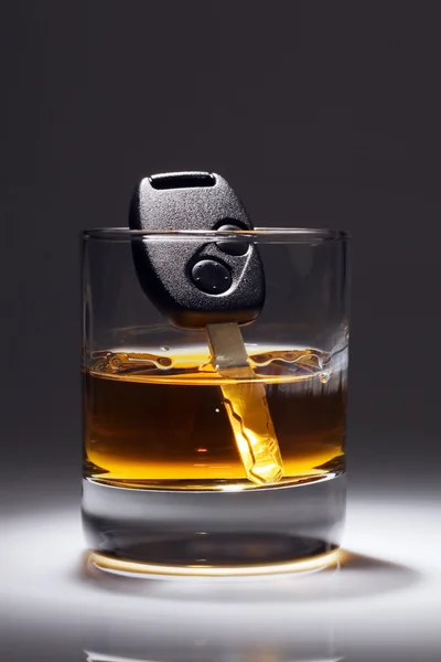 Autosleutels en glas met alcohol — Stockfoto