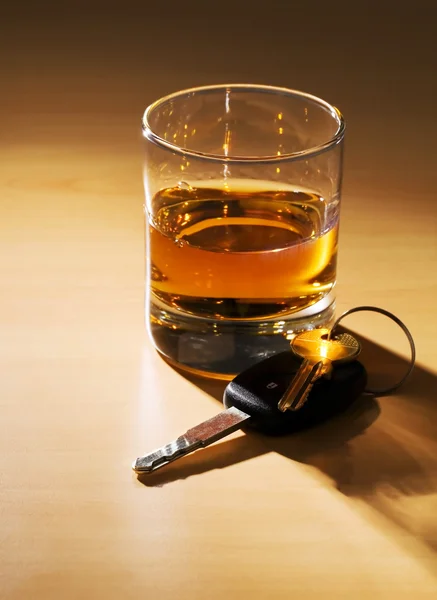 Autosleutels en glas met alcohol — Stockfoto
