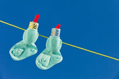 Baby socks on clothesline with swiss francs clipart