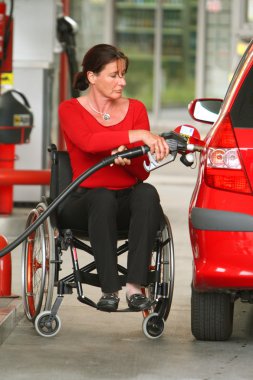 Handicapped woman refuel car at gas station clipart