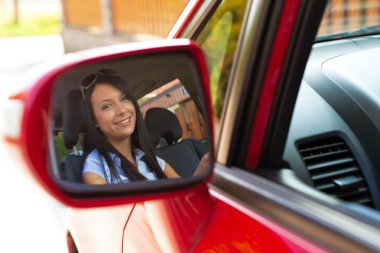 Woman looking in mirror in a car clipart