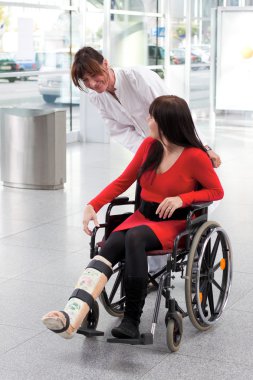 Woman with leg in plaster, wheelchair and carer clipart