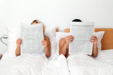 Couple in bed reading newspaper clipart