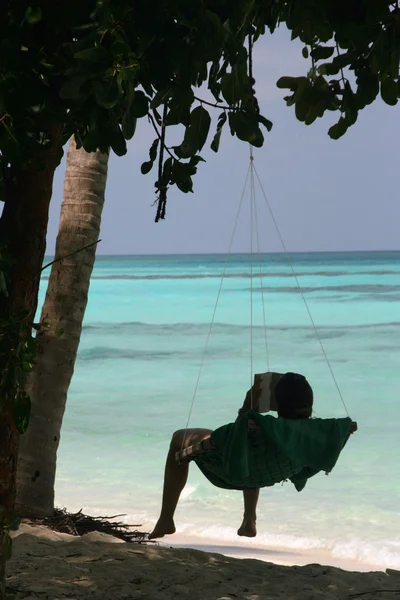 熱帯のビーチでハンモックで本を読んでください。 — ストック写真