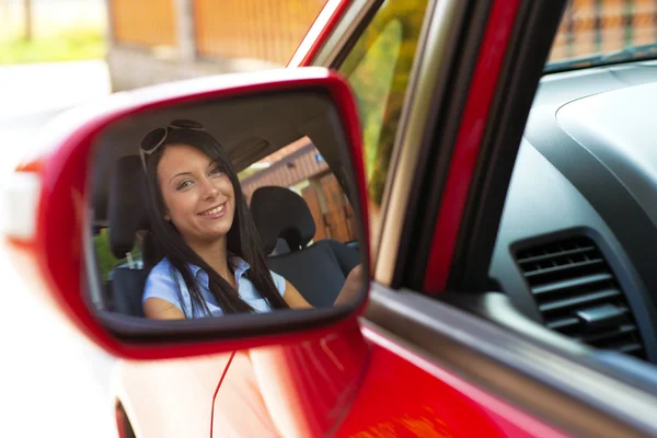Mujer mirando en el espejo en un coche — Foto de Stock