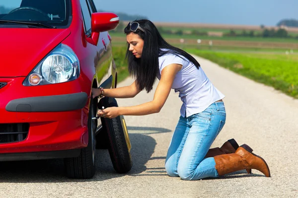 Žena s prázdnou pneumatiku na auto — Stock fotografie