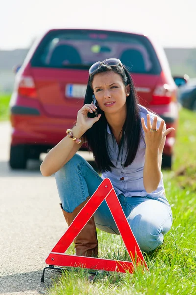 Женщина с предупреждающим треугольником в случае поломки — стоковое фото