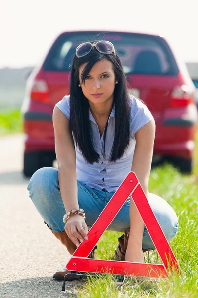 Mulher com um triângulo de aviso em caso de avaria — Fotografia de Stock